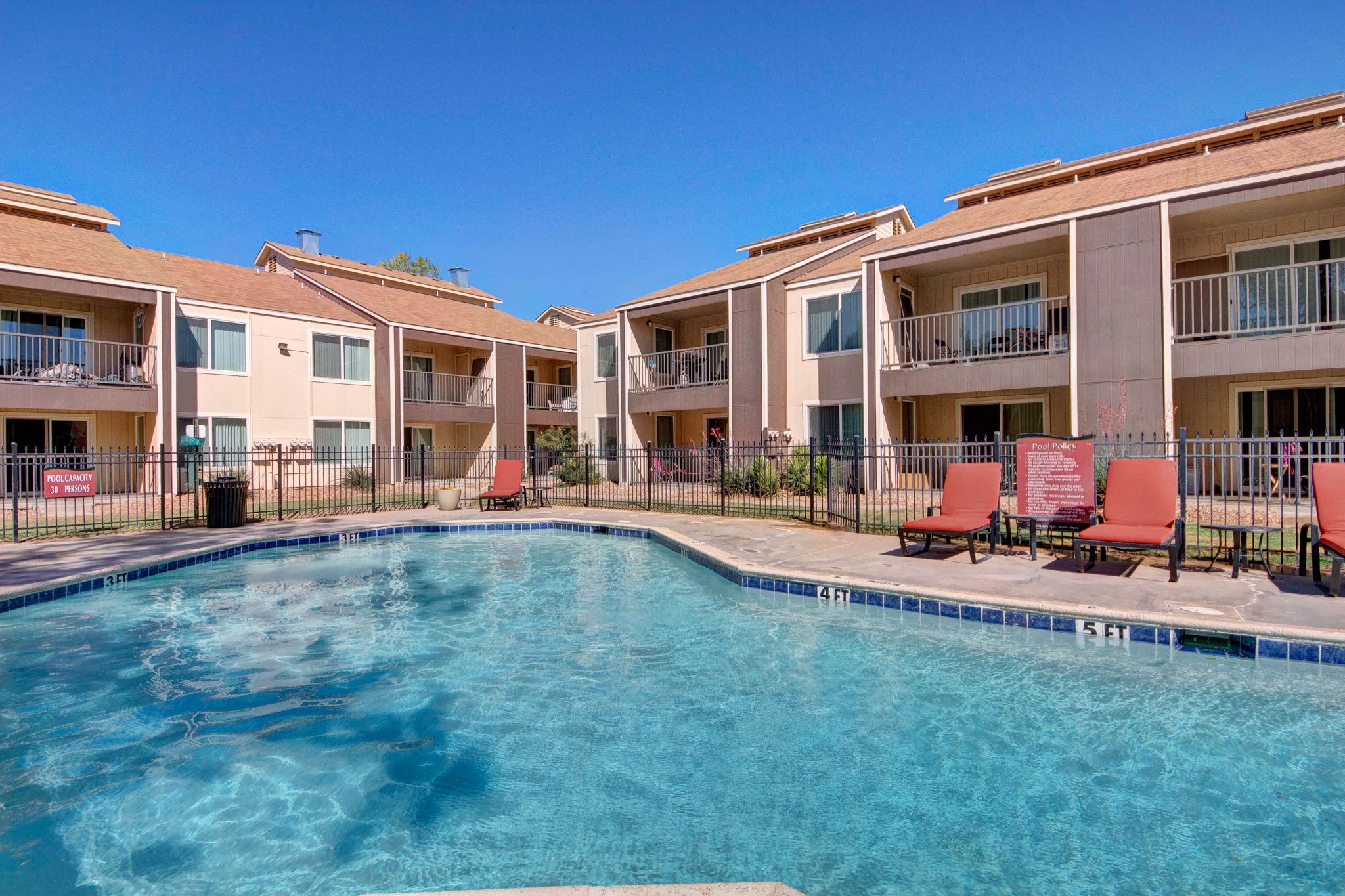 An outdoor pool surrounded by lounge chairs for resident use