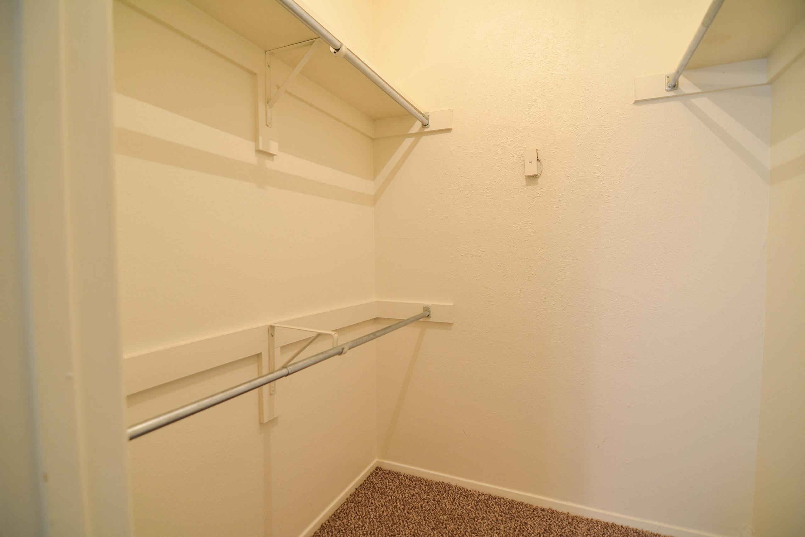 A large walk in closet with multiple shelves and hanger rods