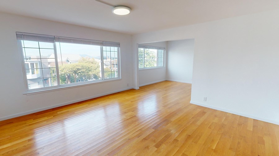 an empty living room with wood floors and large windows
