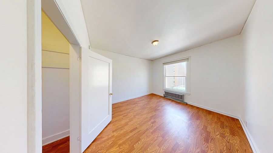 A room with wooden floors and a window with a white frame.