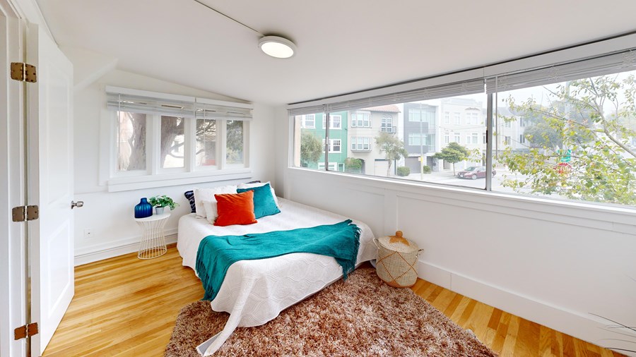 A bedroom with a bed and a window overlooking a street.