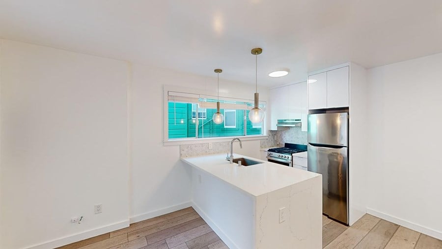 A kitchen with white cabinets and a stainless steel refrigerator.