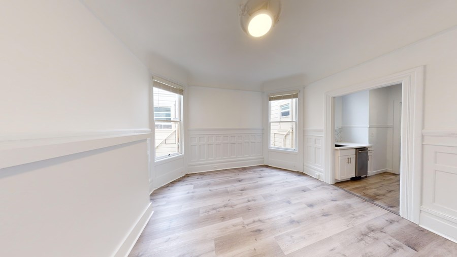 A room with wooden flooring and white walls.