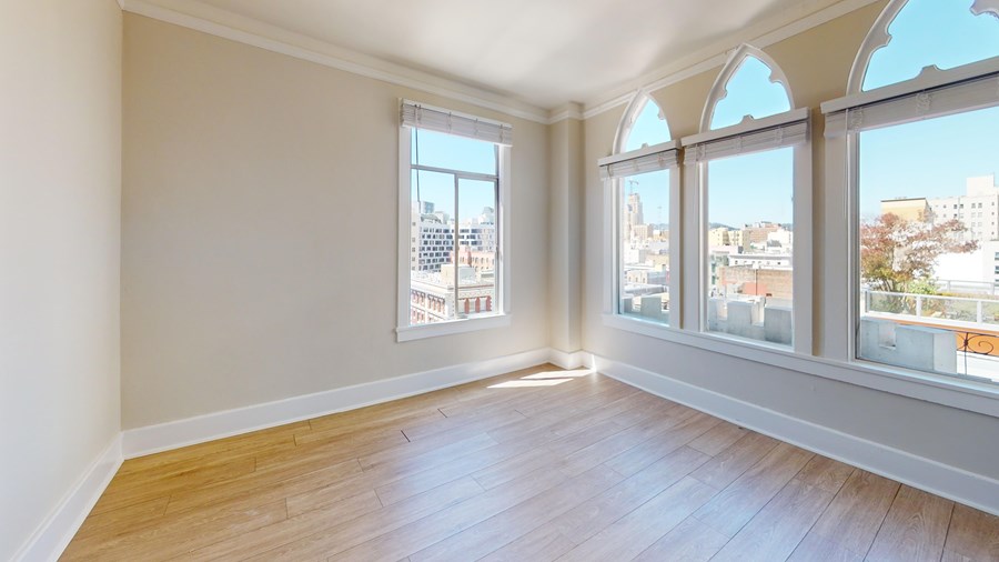 Empty room with large windows overlooking a cityscape.