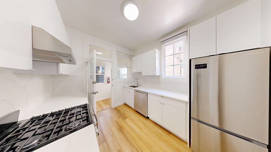 A modern kitchen with a black stove top and white cabinets.