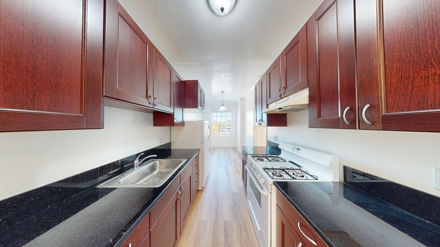 A kitchen with dark wood cabinets and black countertops.
