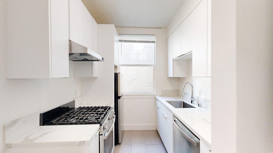 a kitchen with white cabinets and a window