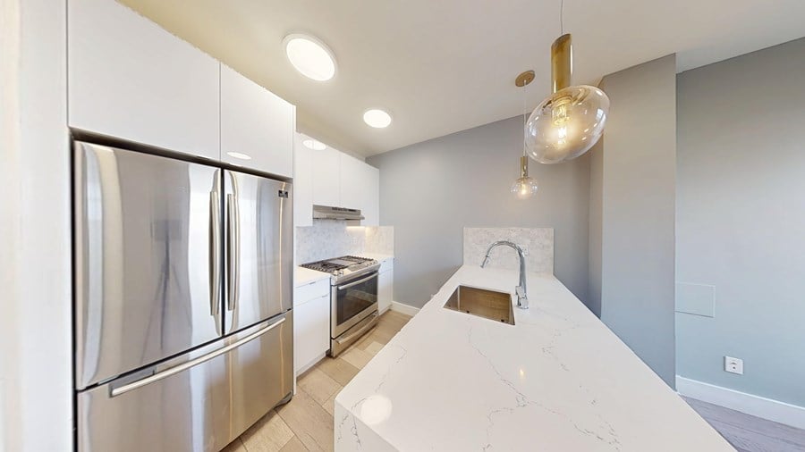 A modern kitchen with a marble countertop and stainless steel appliances.