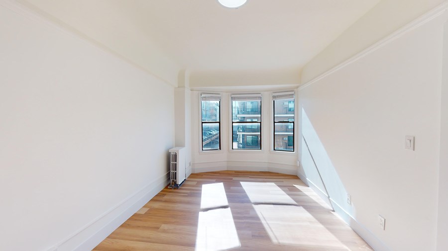 A room with a window and a radiator on the floor.
