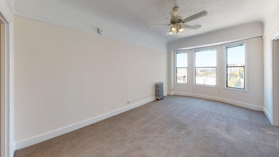 an empty living room with a ceiling fan and windows