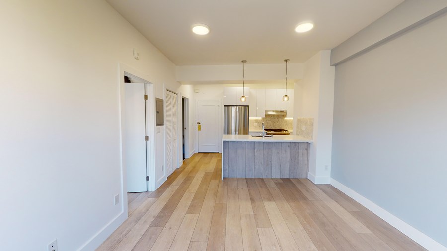 A long, narrow room with a kitchen island in the middle.
