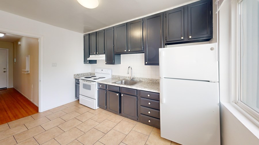 A kitchen with black cabinets and white appliances.