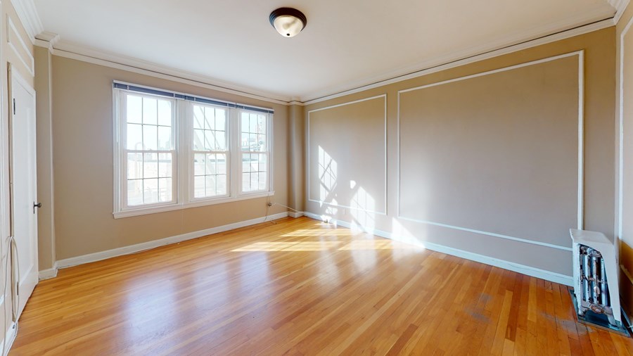 A room with wooden floors and a window letting in sunlight.