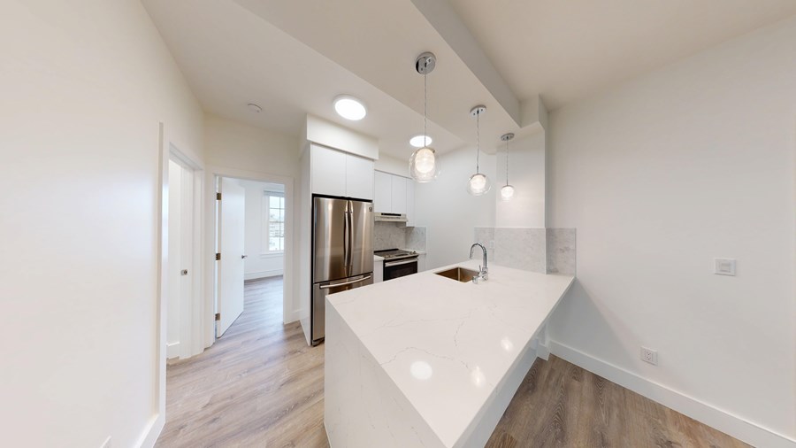 A kitchen with a white countertop and wooden floors.