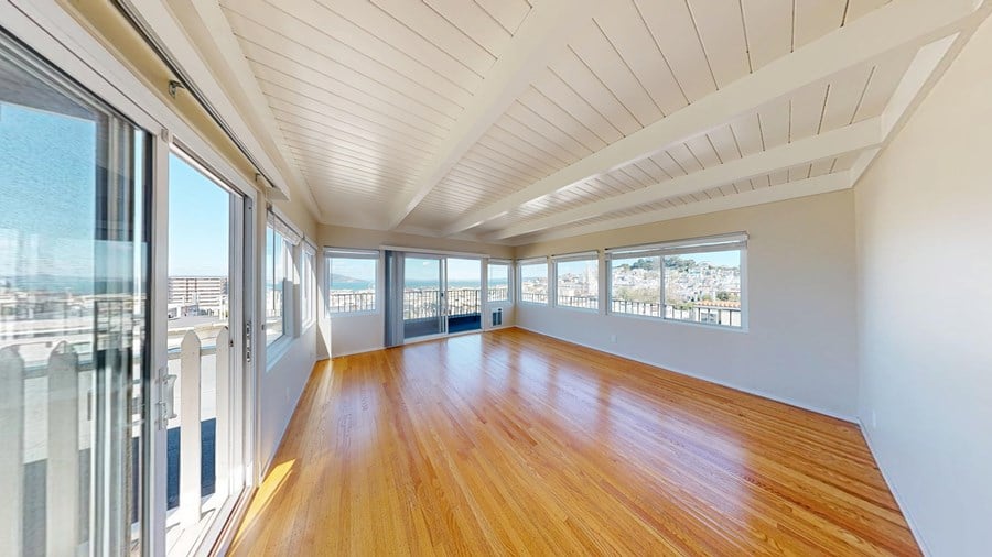 A room with wooden floors and a white ceiling with a long hallway.