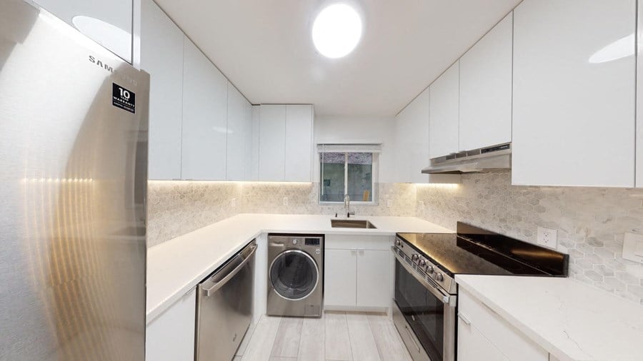 a kitchen with white cabinets and stainless steel appliances and a washing machine