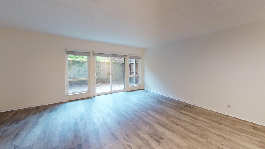 A room with a sliding glass door and wooden flooring.