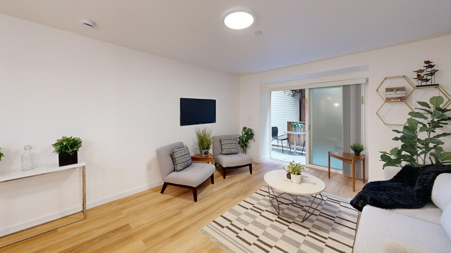 A living room with a white couch, a grey armchair, a white coffee table, and a black and white rug.