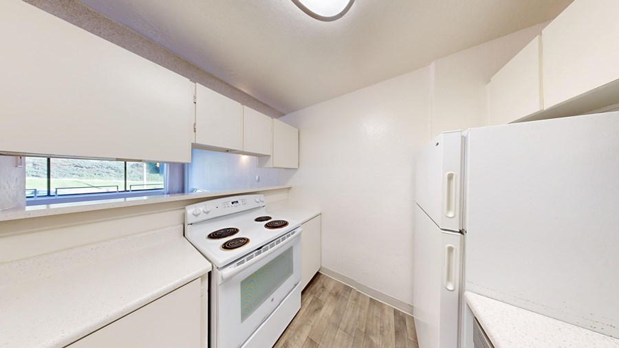 A white kitchen with a stove and a refrigerator.
