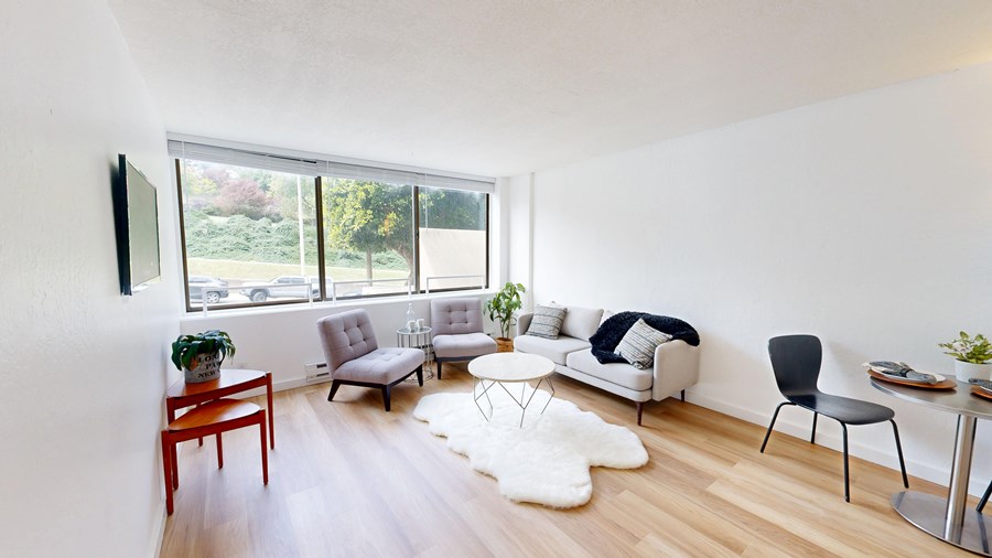 A living room with a white couch, a black chair, and a wooden coffee table.