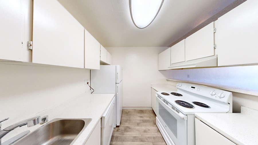 A white kitchen with a stove and sink.