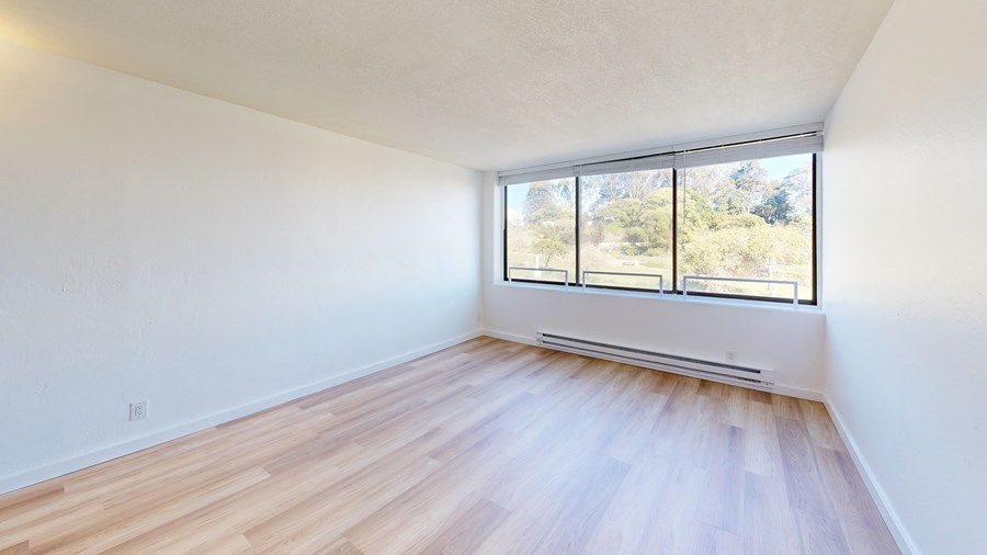 A room with a window overlooking a green area.