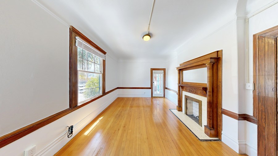 A long, narrow room with wood floors and white walls.