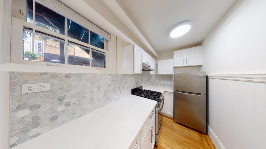 A kitchen with a stainless steel refrigerator and a window.
