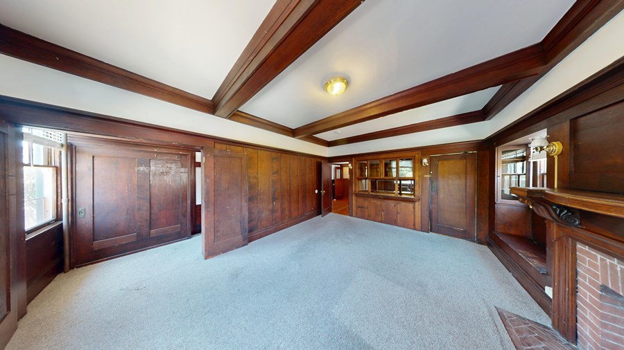 A large empty room with wood paneling and a carpeted floor.