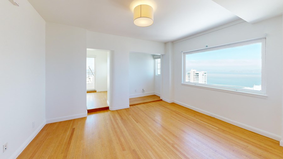 an empty living room with wood floors and a large window