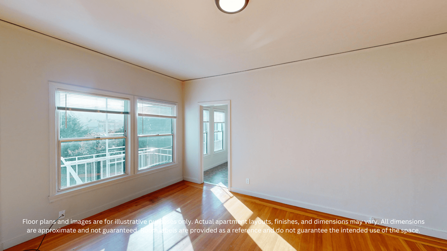 A room with a wooden floor, a door, and a window with a view of a balcony.