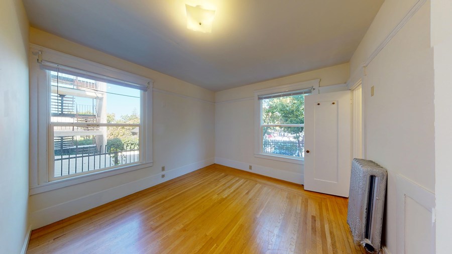 A room with wooden floors and a window overlooking a balcony.