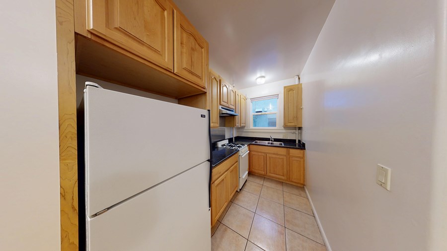 A kitchen with a white refrigerator and wooden cabinets.
