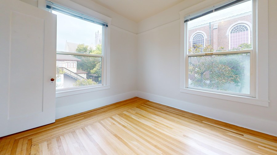 A room with wooden floors and two windows.