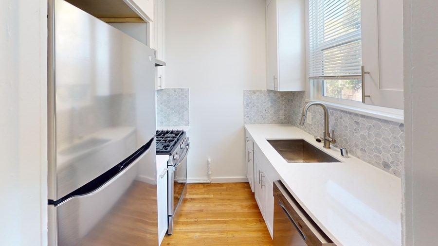 A modern kitchen with a stainless steel refrigerator and wooden floors.