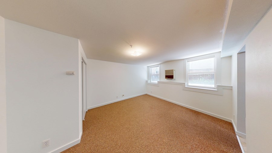 A room with white walls and a brown carpet.