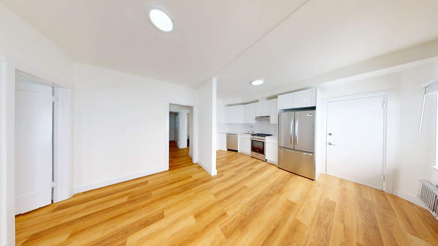 A kitchen with white walls and wooden floors.