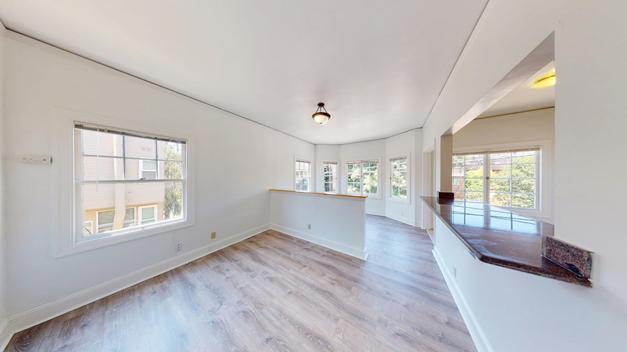 A spacious room with wooden floors and large windows.