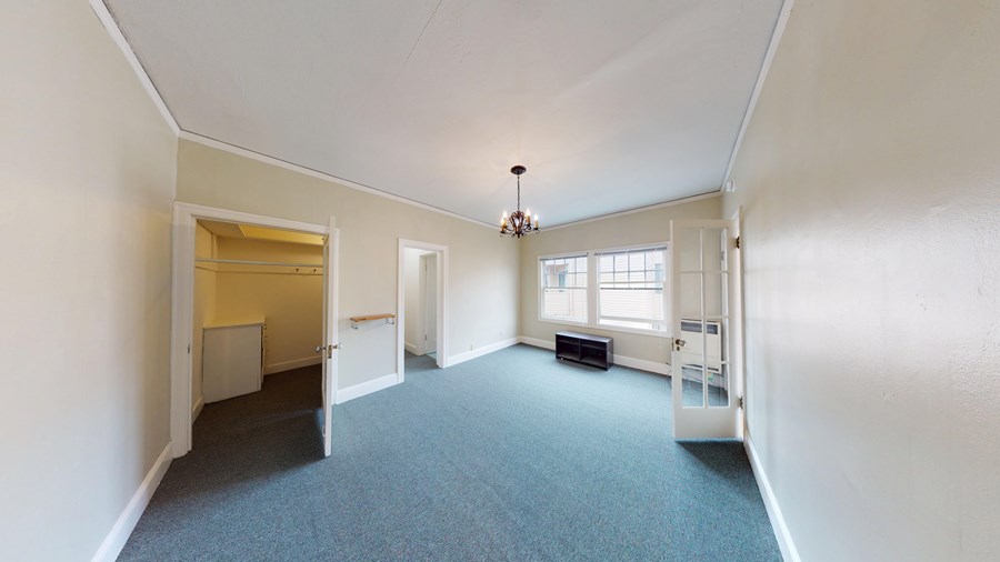 A large empty room with a chandelier and a window.