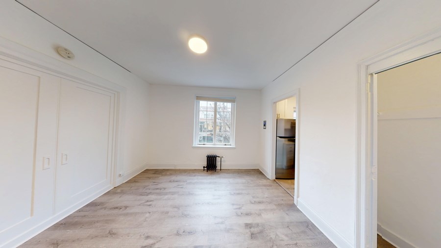 A large empty room with a window and a door.