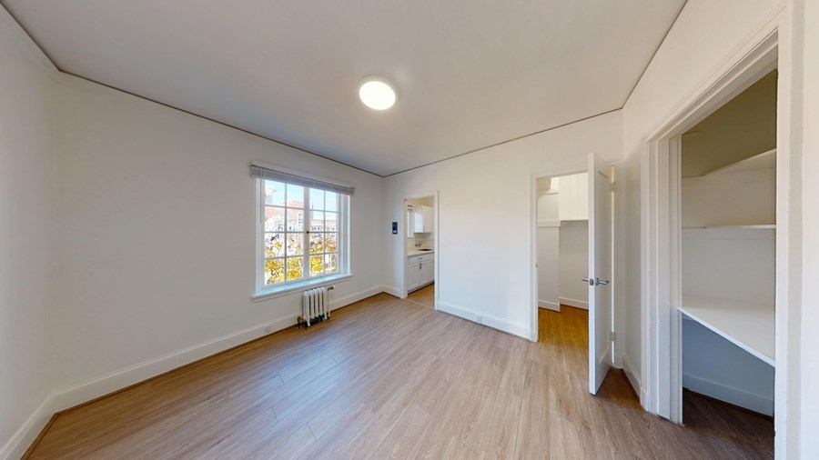 A room with wooden floors and a window with a view of a building outside.