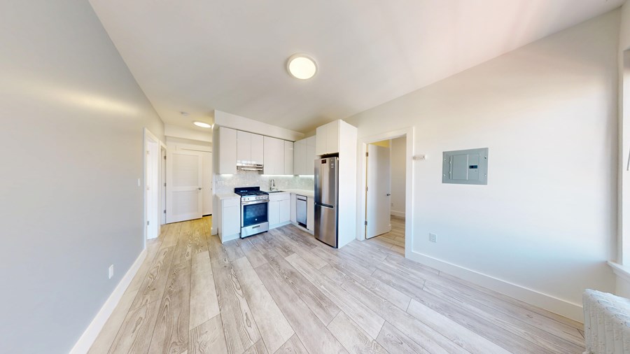A kitchen with a refrigerator, oven, and sink is visible in the image.