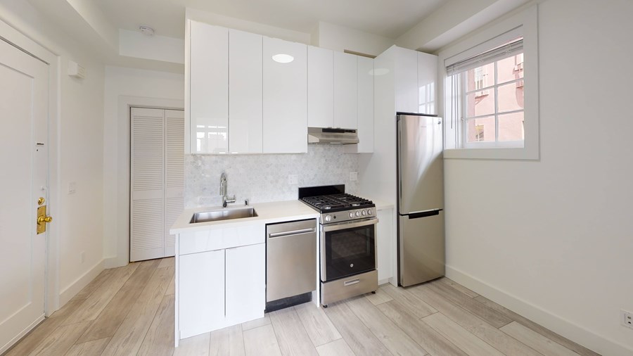 A modern kitchen with white cabinets and stainless steel appliances.