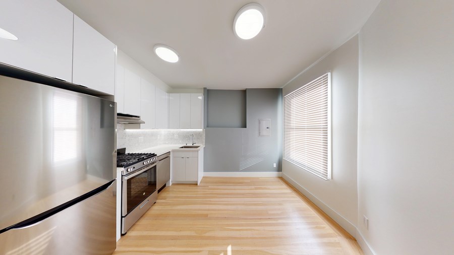 A modern kitchen with wooden floors and stainless steel appliances.