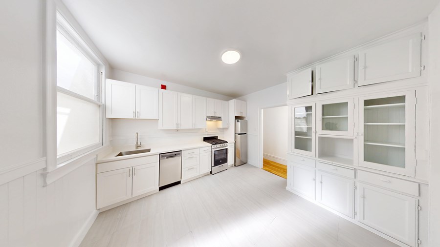 A white kitchen with a dishwasher, oven, and sink.