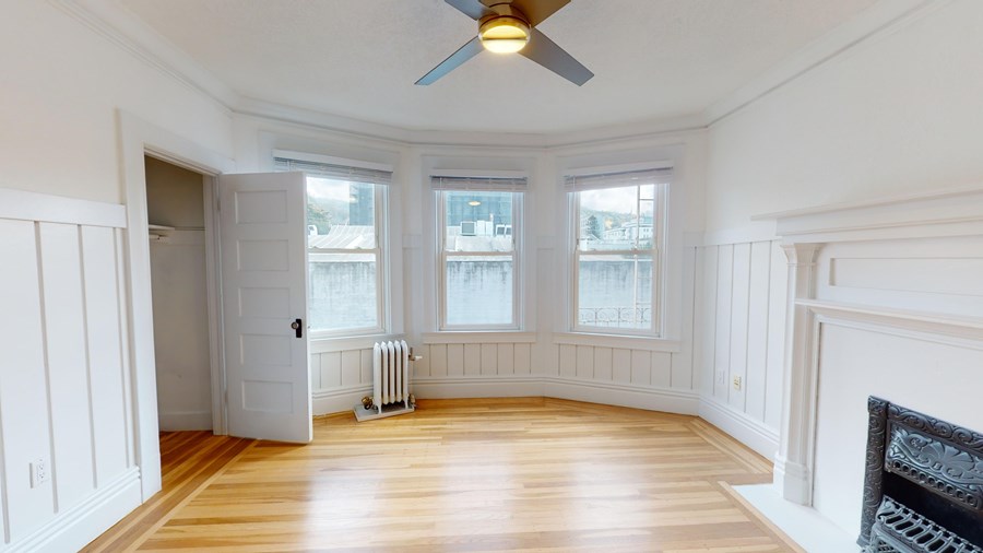A room with a ceiling fan and a fireplace.