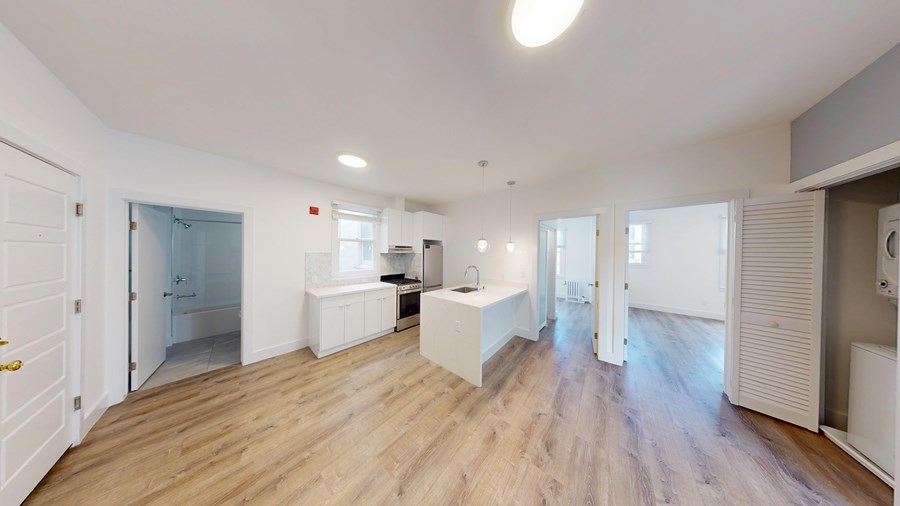 A spacious room with wooden floors and white walls.