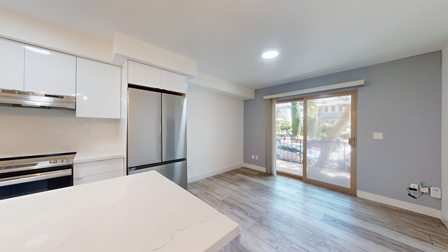 A kitchen with white cabinets and a stainless steel refrigerator.