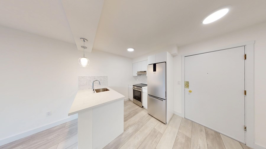 A kitchen with white cabinets and a white fridge.