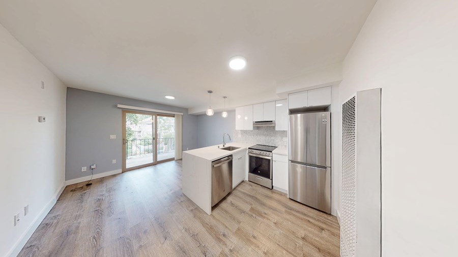 A modern kitchen with stainless steel appliances and wooden flooring.